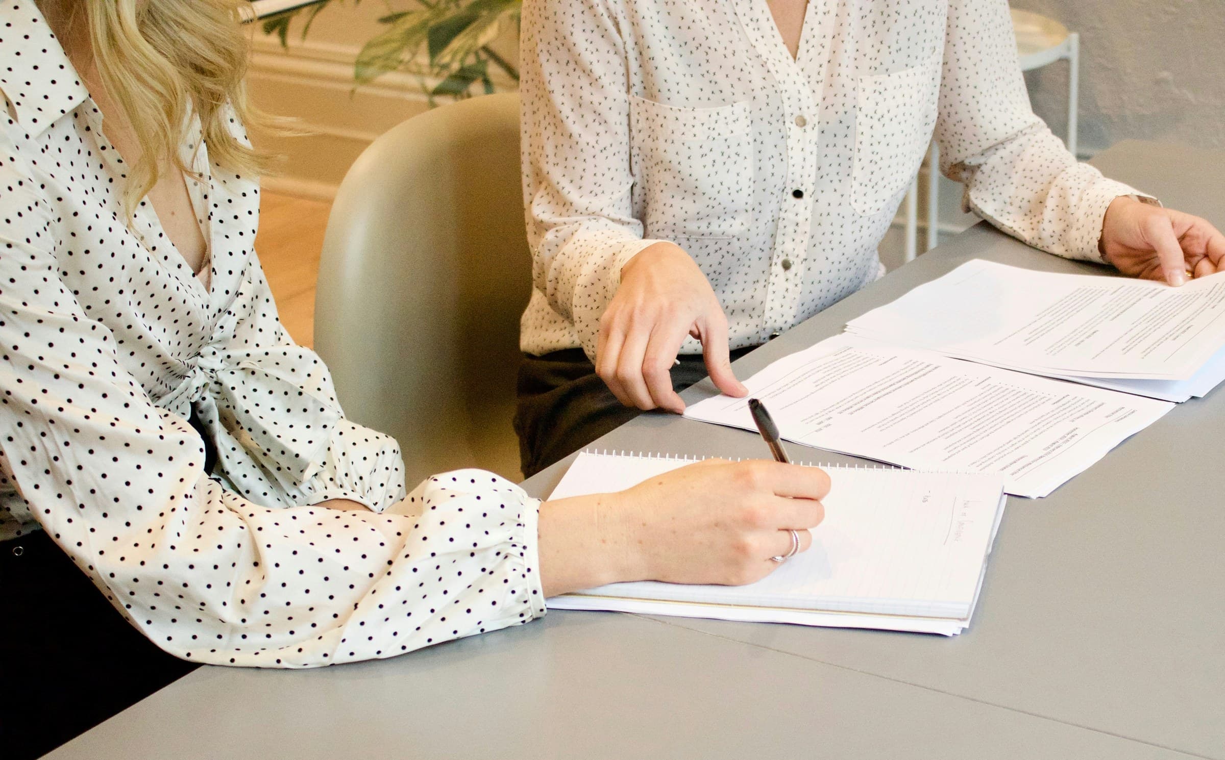 Zwei Personen sitzen an einem hellen Besprechungstisch und gehen gemeinsam Unterlagen durch