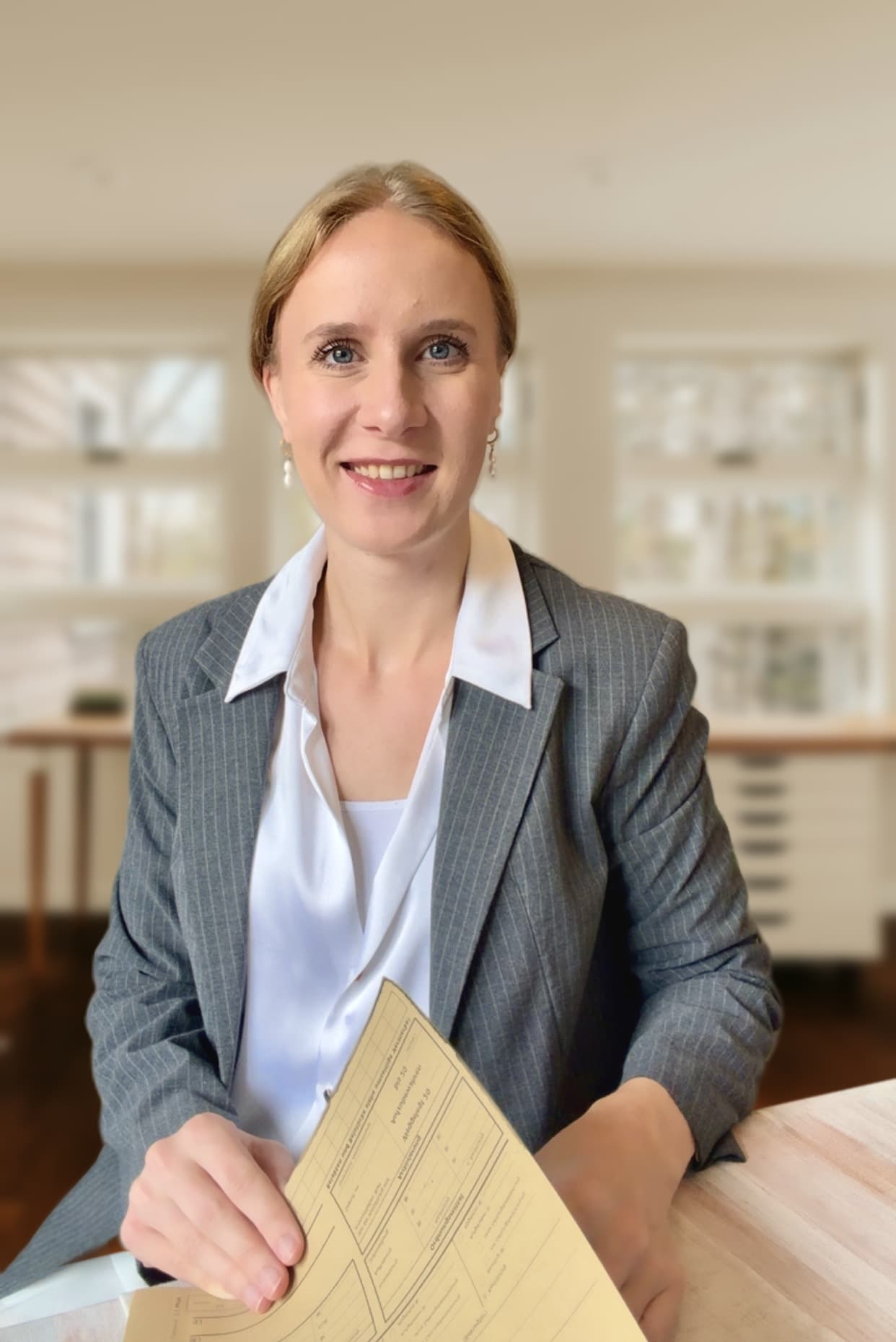 Muriel Dewidar sitzt am Schreibtisch und hält eine Akte